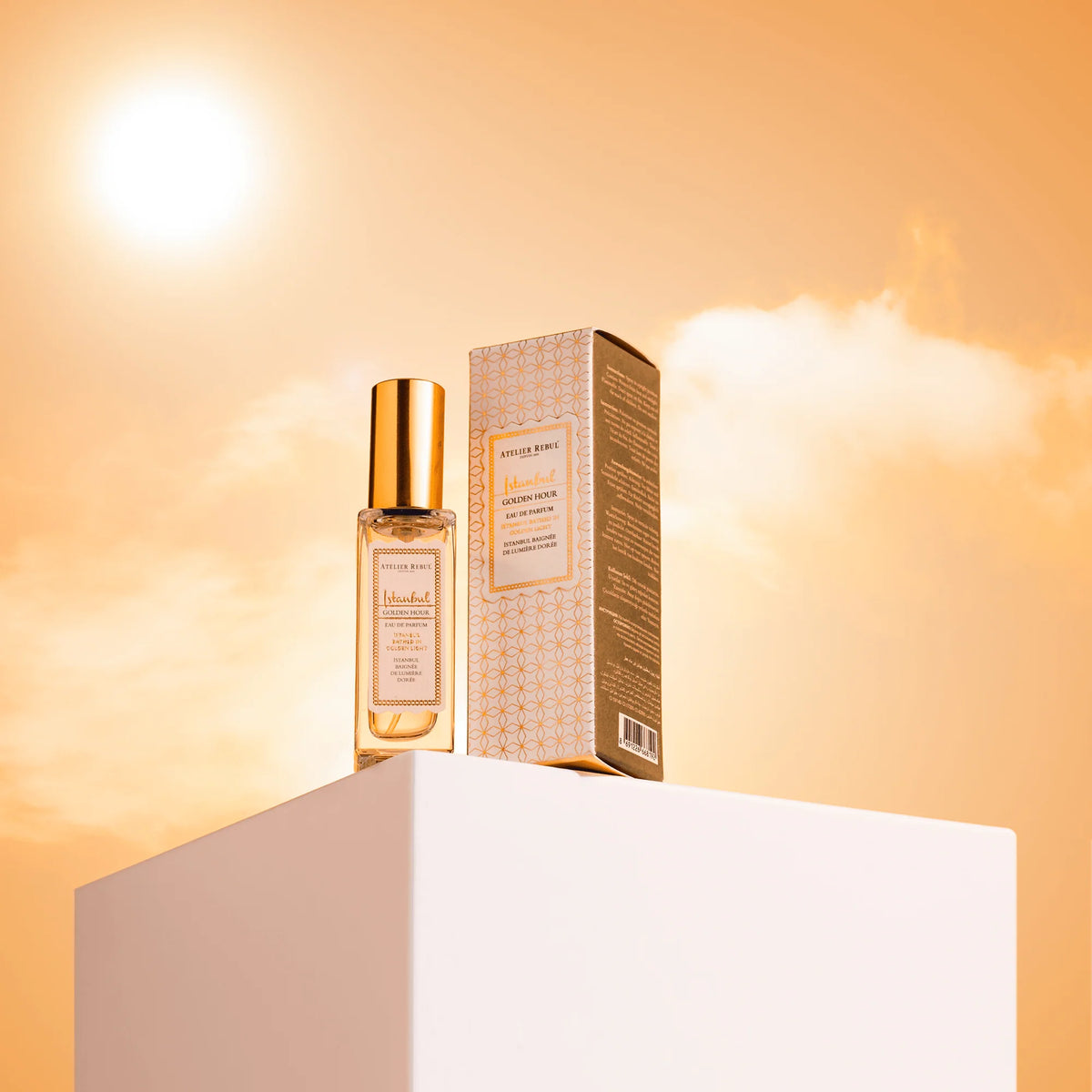 Istanbul Golden Hour Eau de Parfum 12 ml mit goldener Kappe und Verpackung auf weißem Podest vor goldenem Himmel.