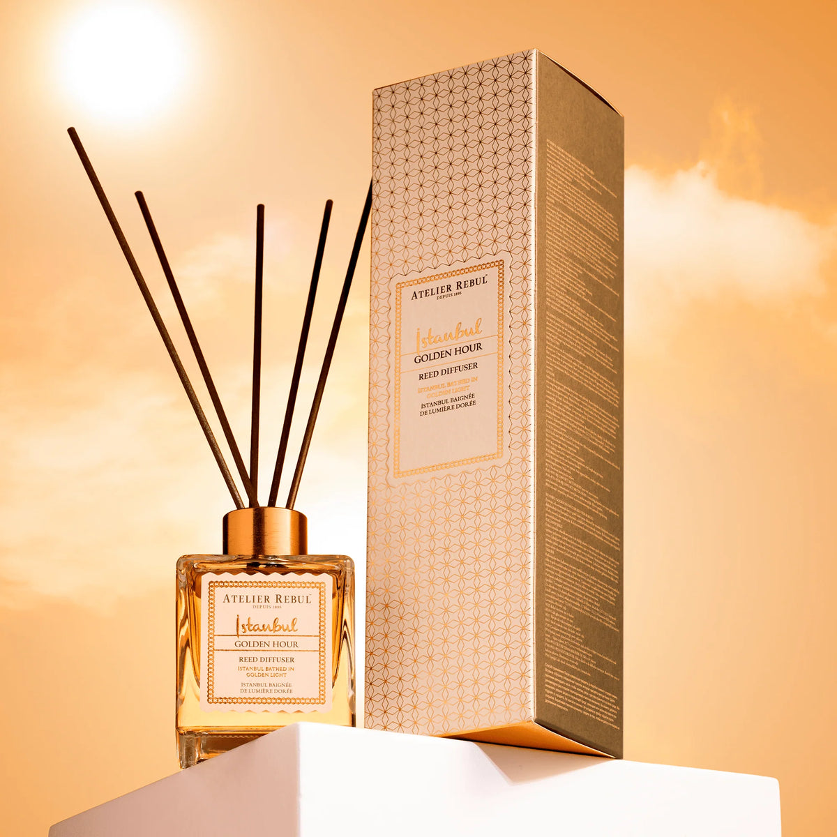 Atelier Rebul Istanbul Golden Hour Raumdiffusor 120 ml mit Duftstäbchen und Verpackung auf weißem Podest im goldenen Licht.