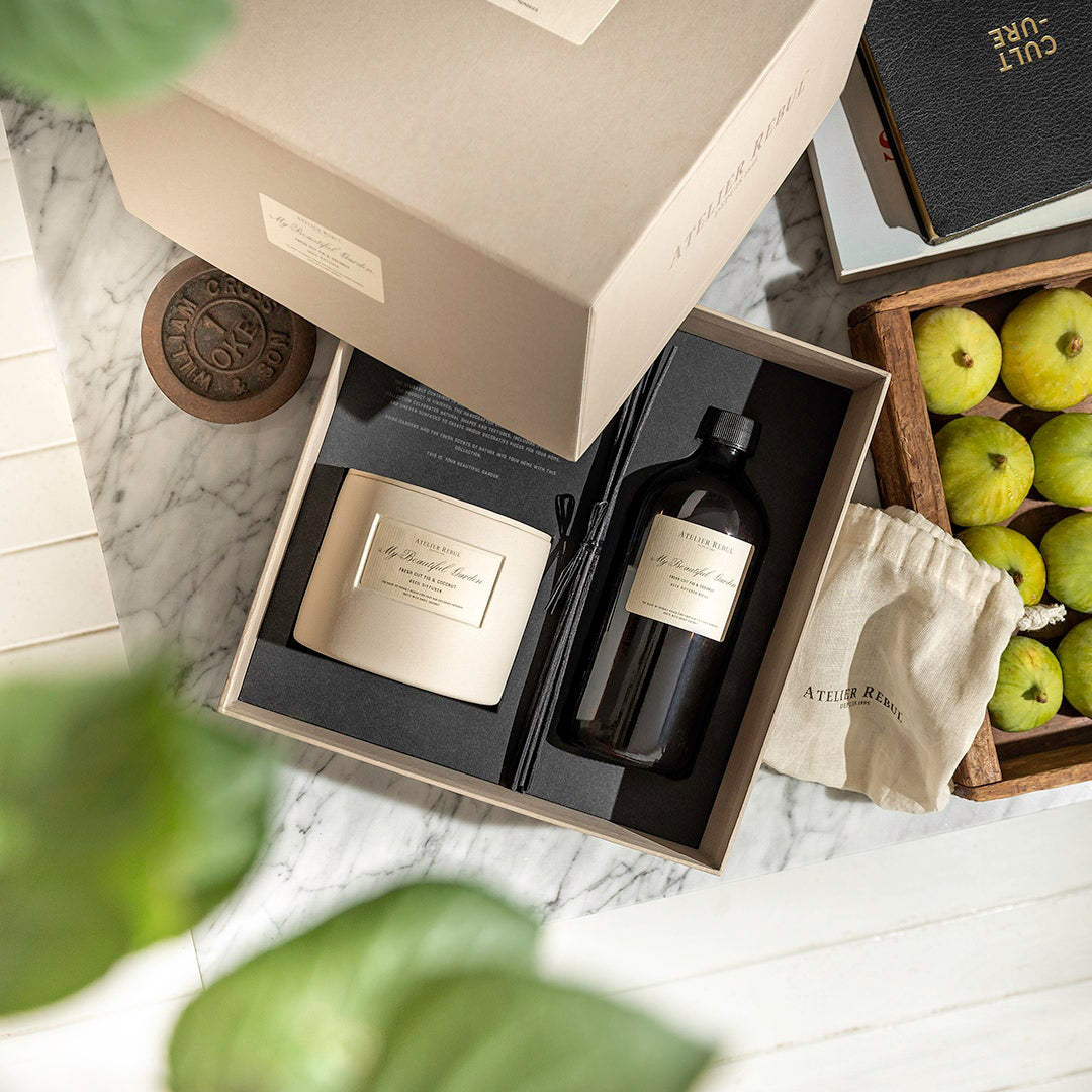 geoeffnete geschenkbox darin liegen die staebchen, flasche und gefaess auf einem dekorierten mamortisch