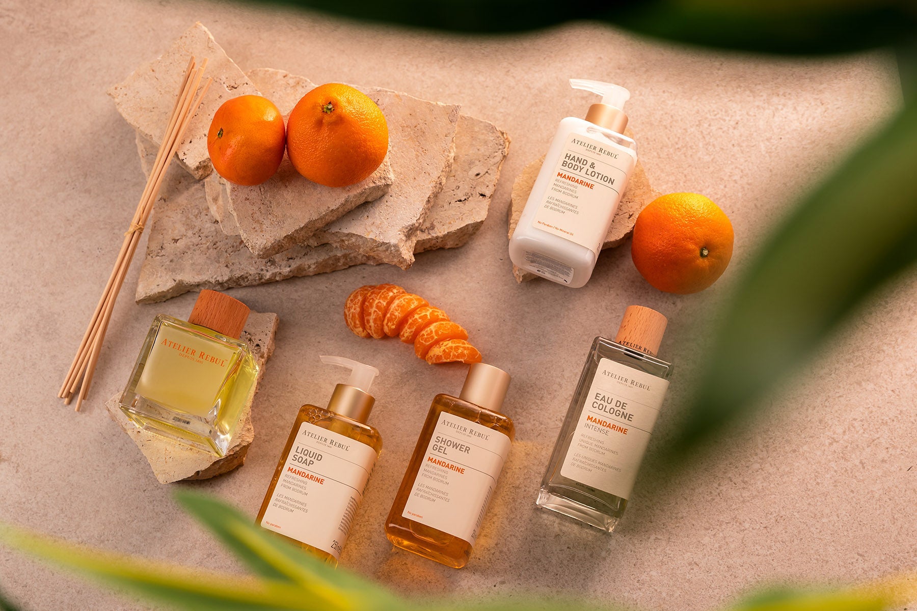 zwischen mandarinen und stueckchen liegen verschiedene atelier rebul produkte auf einem sandfarbenen stein