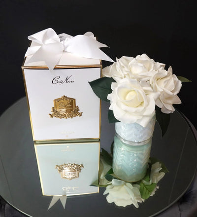 weisse herringbone duftblume neben geschenkbox auf rundem, spiegelndem tisch. obersicht.