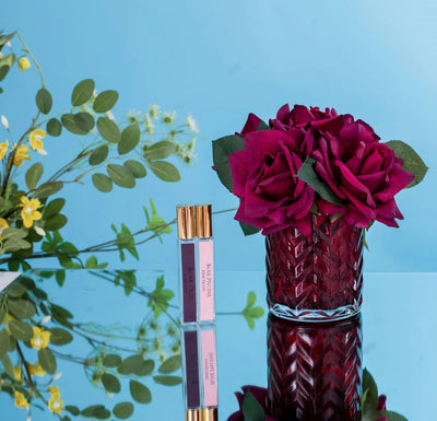 rote herringbone duftblume neben zwei parfumsprays und strauch. blauer hintergrund.