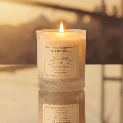 Brennende Atelier Rebul Istanbul Golden Hour Duftkerze 210 g im cremefarbenen Glas auf einer spiegelnden Oberfläche.