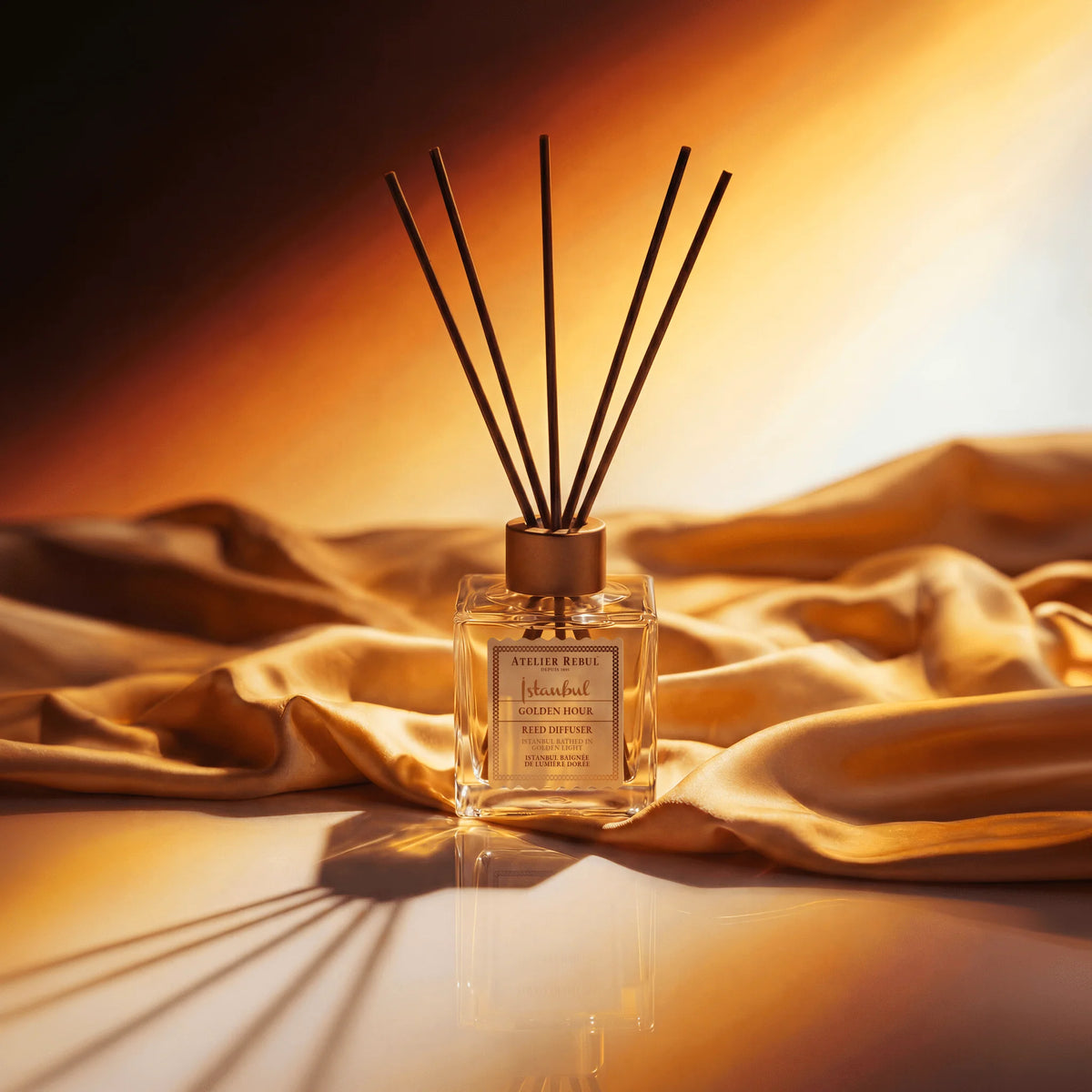 Atelier Rebul Istanbul Golden Hour Raumdiffusor 120 ml mit Duftstäbchen auf goldenem Stoff.