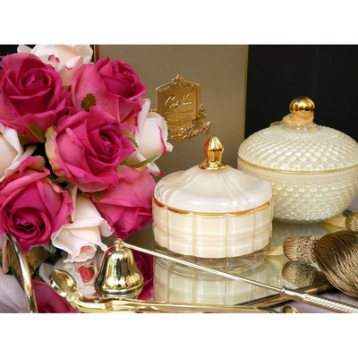 Luxuriöse Duftkerze Blonde Vanilla mit goldenem Zubehör, Rosen und schwarzer Vase auf Tablett