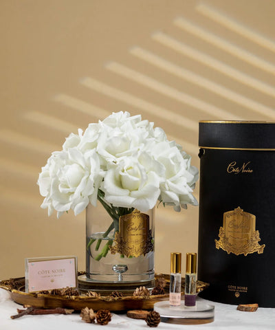 Eleganter Duftrosenstrauß in Elfenbeinweiß mit goldener Verzierung in luxuriöser schwarzer Geschenkbox – stilvoll arrangiert im warmen Licht.
