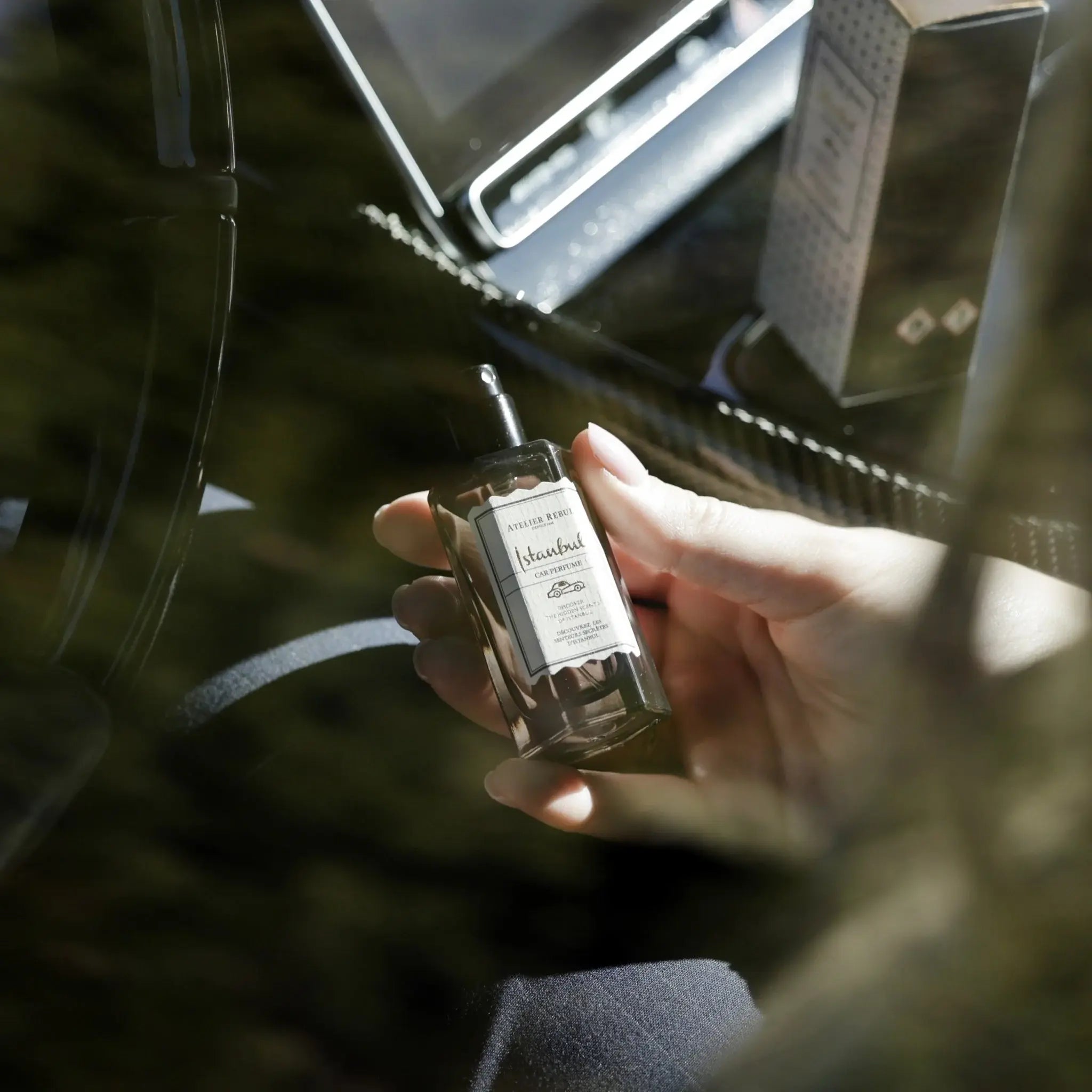 Hand sprüht das Istanbul Auto Parfum von Atelier Rebul in einem edlen Autoambiente.