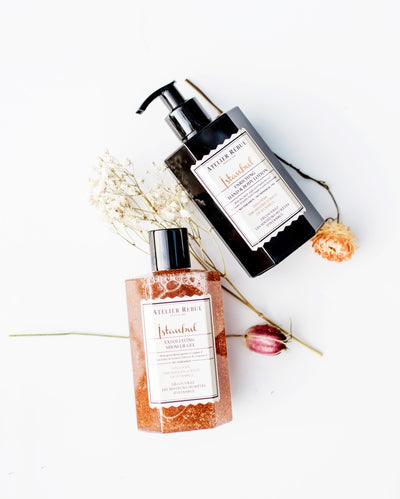 istanbul hand und bodylotion in schwarzer pumpflasche mit istanbul duschgel mit peeling auf weissem hintergrund mit blumen.
