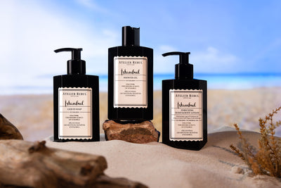 istanbul hand und bodylotion in schwarzer pumpflasche mit fluessigseife und duschgel auf sand und steinen 