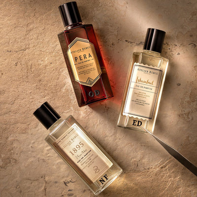 3 verschiedene eau de parfum von atelier rebul liegen auf einem hellen steinboden