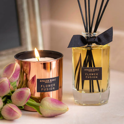 verschwommener hintergrund vorne ein strauss tulpen die brennende duftkerze daneben duftstaebchen in einer glasflasche