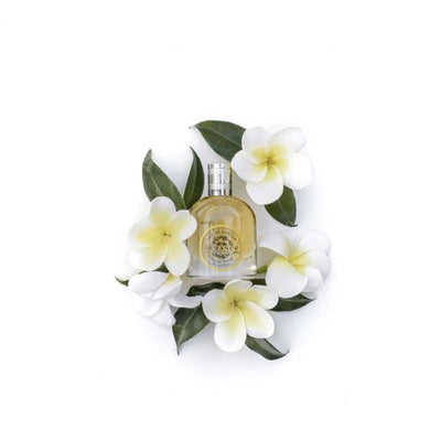 vor einem weissen hintergrund steht die edp flasche monoi die von weissen blumen umhuellt wird