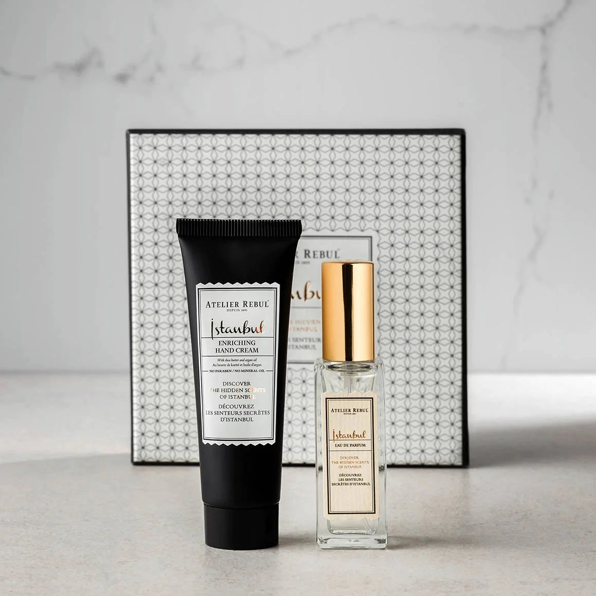 frontansicht der schwarzen handcreme tube und hellen parfuemflasche mit goldenem deckel.
