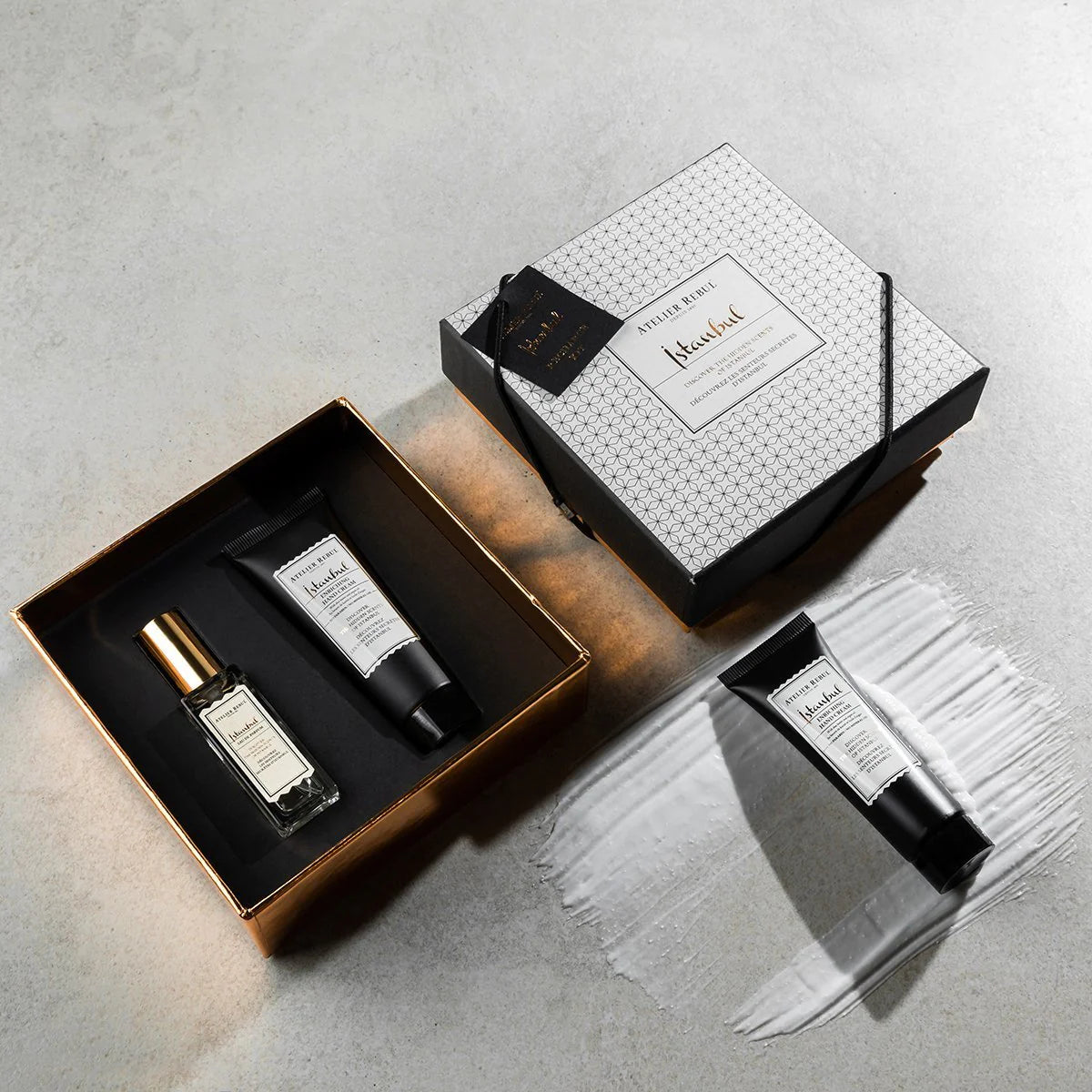 geoeffnete miniature box auf boden. eine handcreme liegt auf pinselstrich der creme.