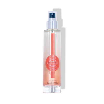 durchsichtige runde glasflasche eau fraiche schoene mohnbluete  mit silbernen spruehkopf vor weissem hintergrund
