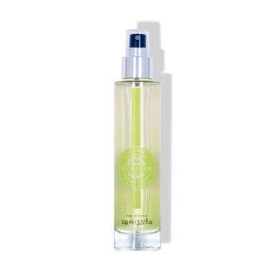 durchsichtige runde glasflasche eau fraiche prickelnde verbene mit silbernen spruehkopf vor weissem hintergrund